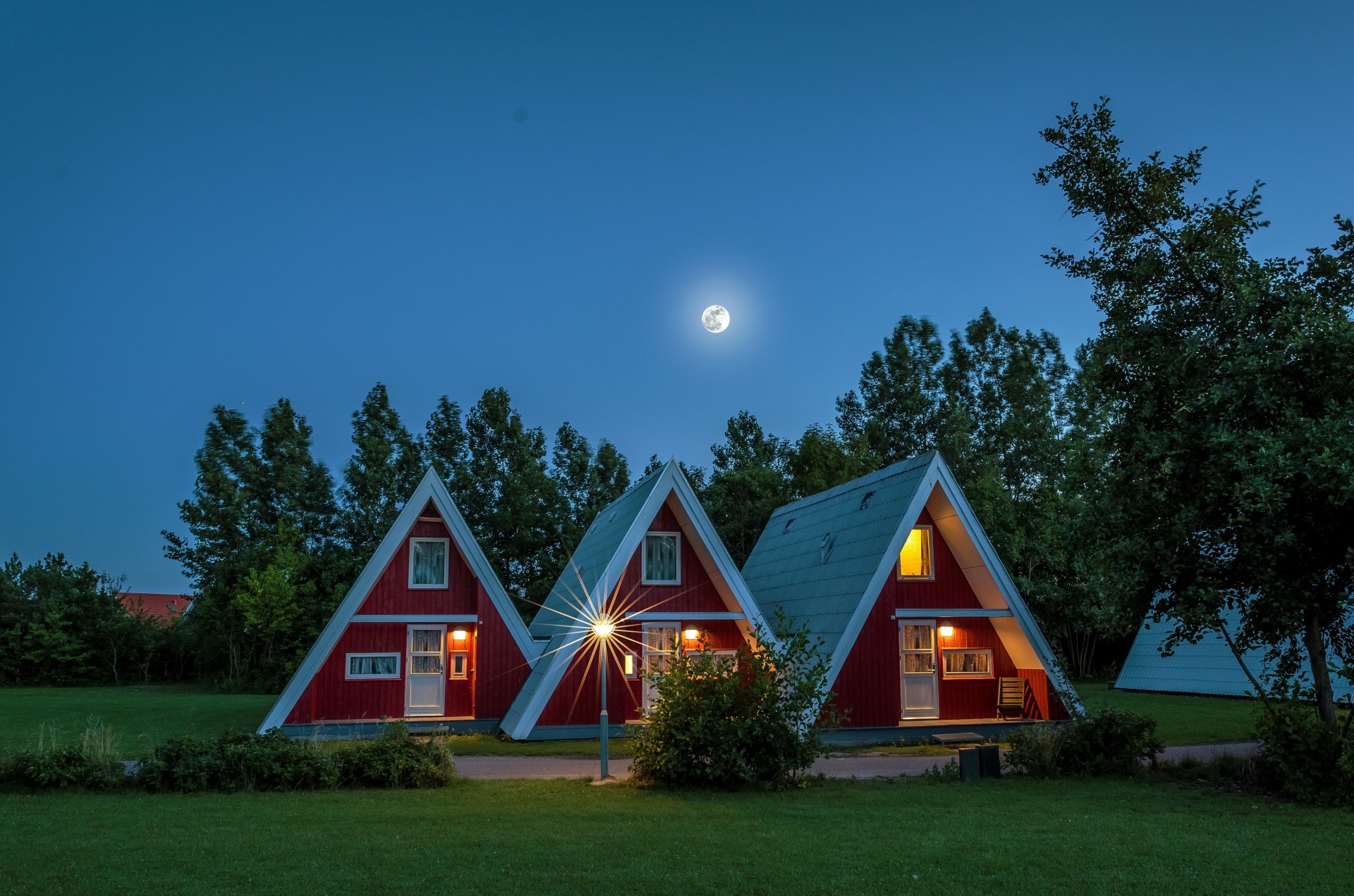 A serene HD desktop wallpaper depicting moonlit triangular houses nestled among trees in Germany, showcasing unique architecture.