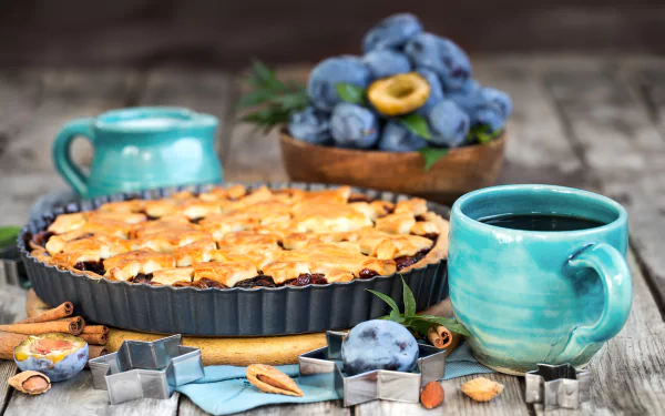 A 4K Ultra HD still life featuring a plum pie, fresh plums in a bowl, a steaming cup of coffee in a turquoise cup, and pastry tools arranged on a rustic wooden table.