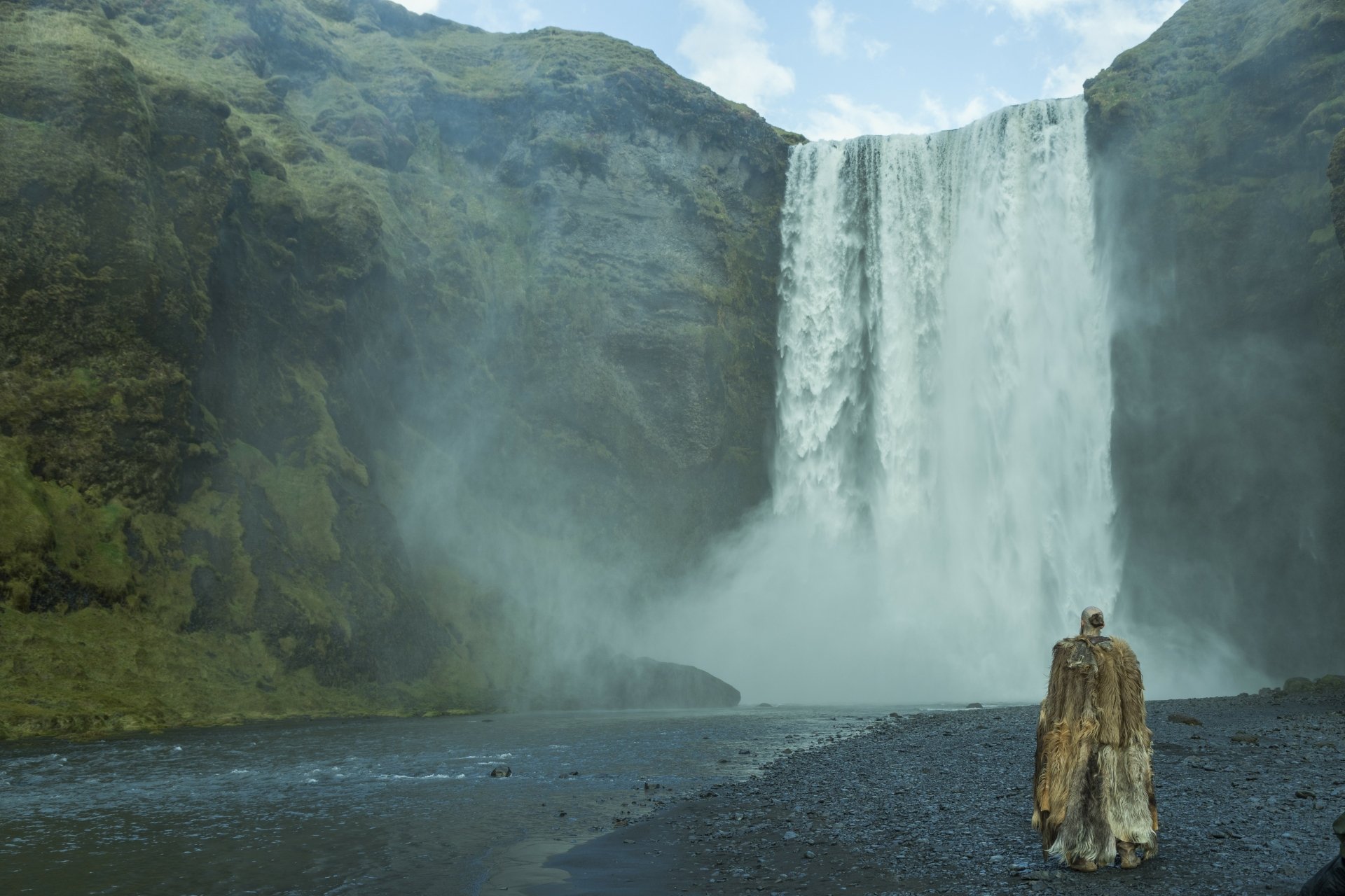 Scenic 4K Ultra HD desktop wallpaper from the TV show Vikings (2013), featuring a lone figure in fur cloak standing before a powerful waterfall amidst rugged cliffs.