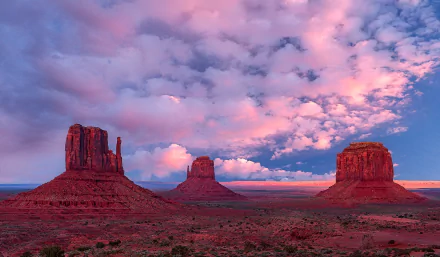 HD desktop wallpaper showcasing Utah's Monument Valley desert landscape under a vibrant sky filled with scattered clouds at sunset in the USA.