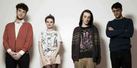 HD desktop wallpaper of Clean Bandit posing for an informal group photo against a light background.