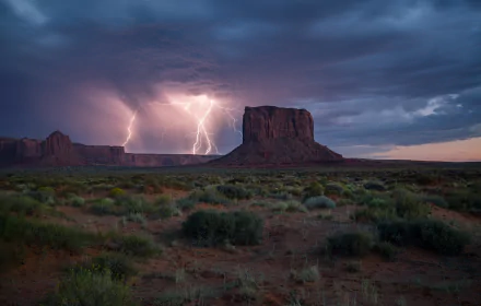 HD wallpaper of Monument Valley in Utah, USA, showcasing a dramatic desert landscape under a stormy sky with striking lightning amidst clouds.