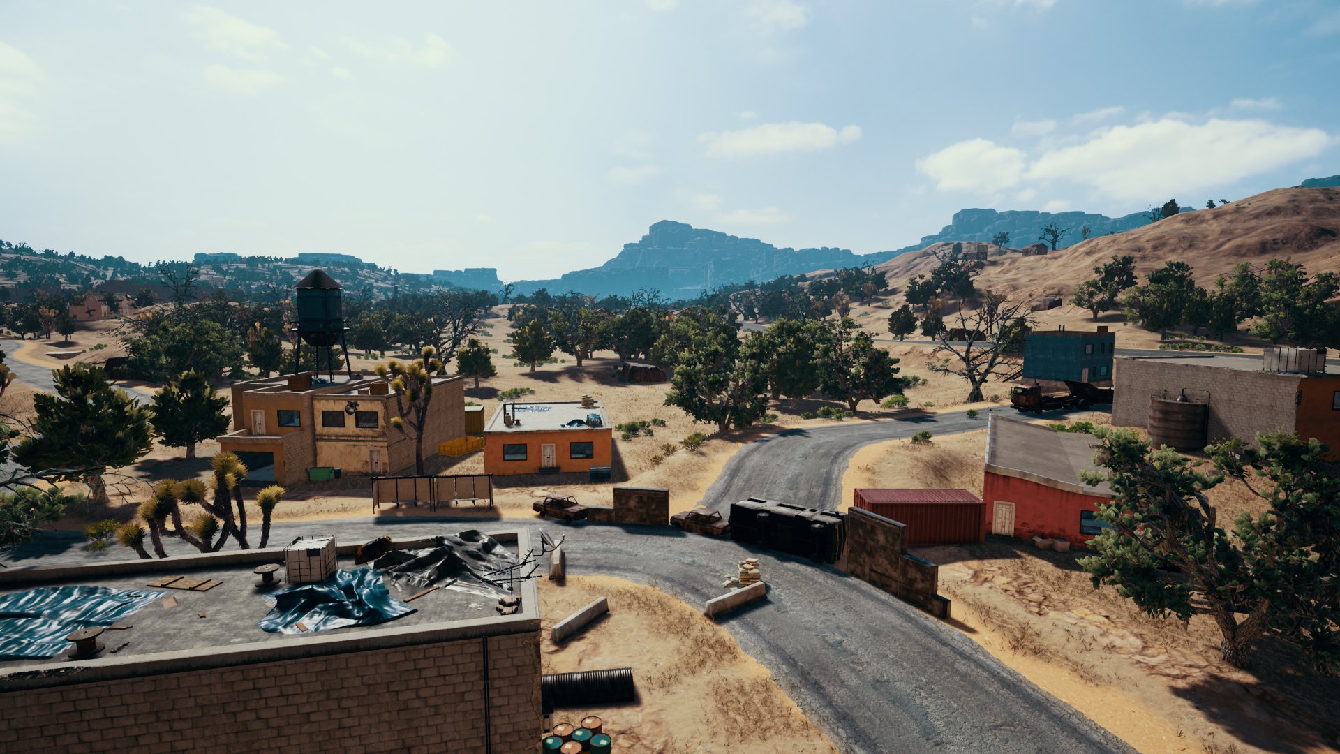 HD desktop wallpaper from PlayerUnknown's Battlegrounds, showcasing a scenic in-game landscape with buildings, trees, and mountainous terrain.
