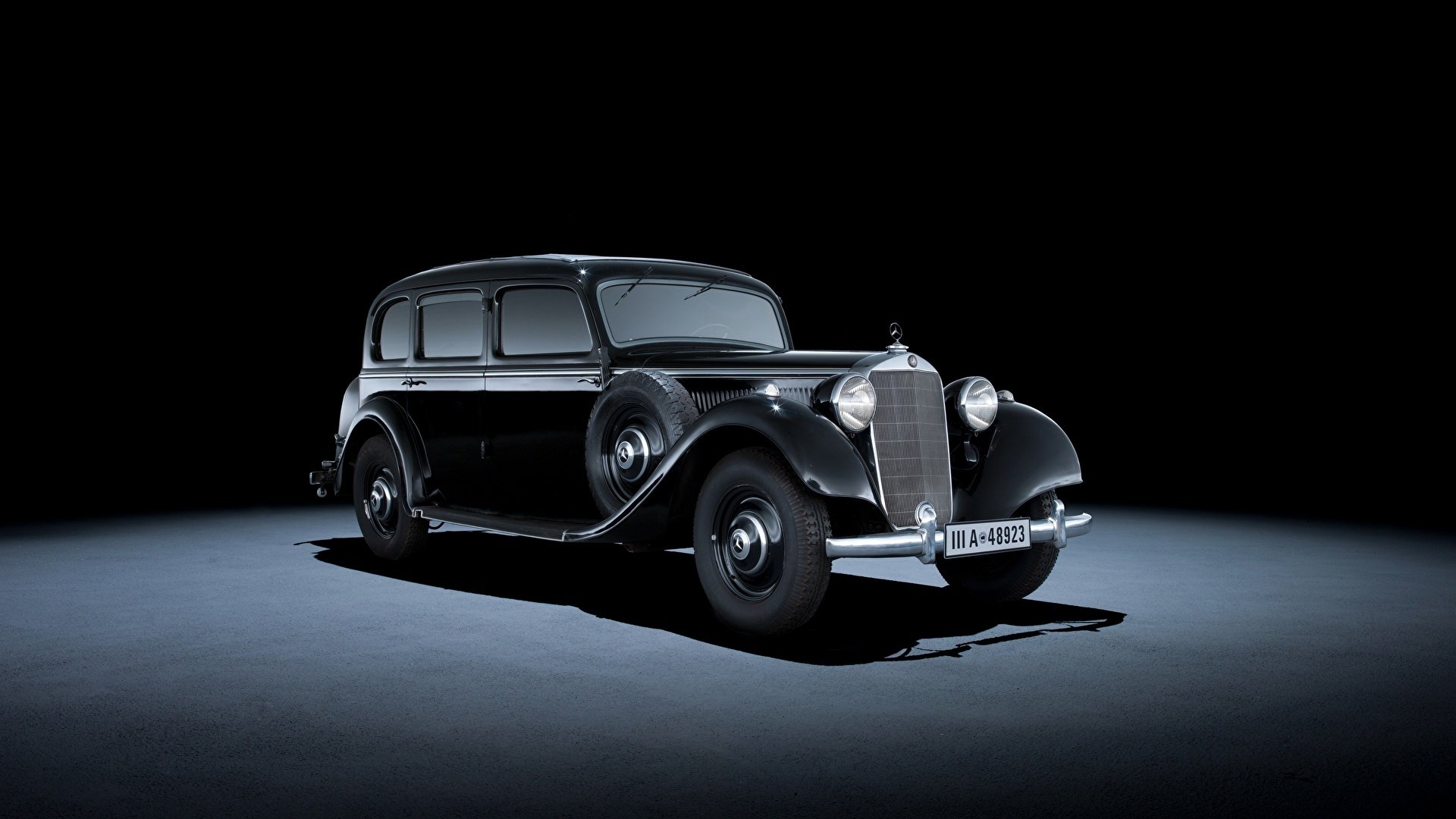 Classic black Mercedes-Benz vehicle centered on a dark studio stage, shot in high definition — PC desktop wallpaper/background.