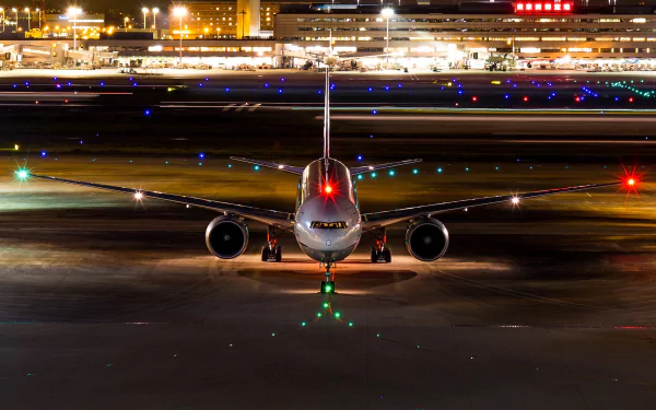 An HD desktop wallpaper of a passenger plane on a runway at night, with airport lights in the background, showcasing the aircraft in a vibrant and dynamic airport setting.