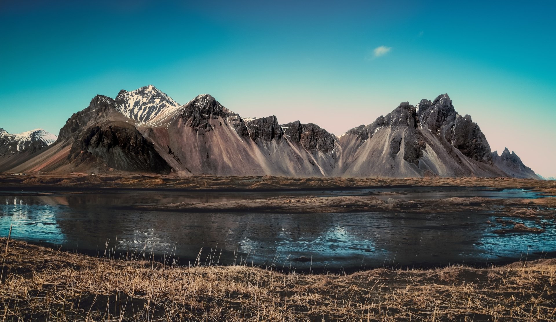 A stunning HD landscape desktop wallpaper featuring towering mountains, a calm reflective lake, and vibrant sky, presenting the beauty of nature.
