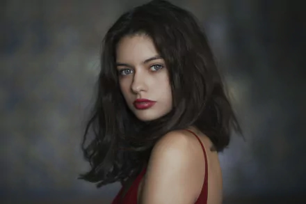 HD desktop wallpaper of a brunette woman with blue eyes and red lipstick, featuring a close-up portrait against a dark, blurred background.