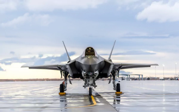 Front view of a Lockheed Martin F-35 Lightning II jet fighter warplane on a wet runway under a cloudy sky, captured in HD for a PC desktop wallpaper.