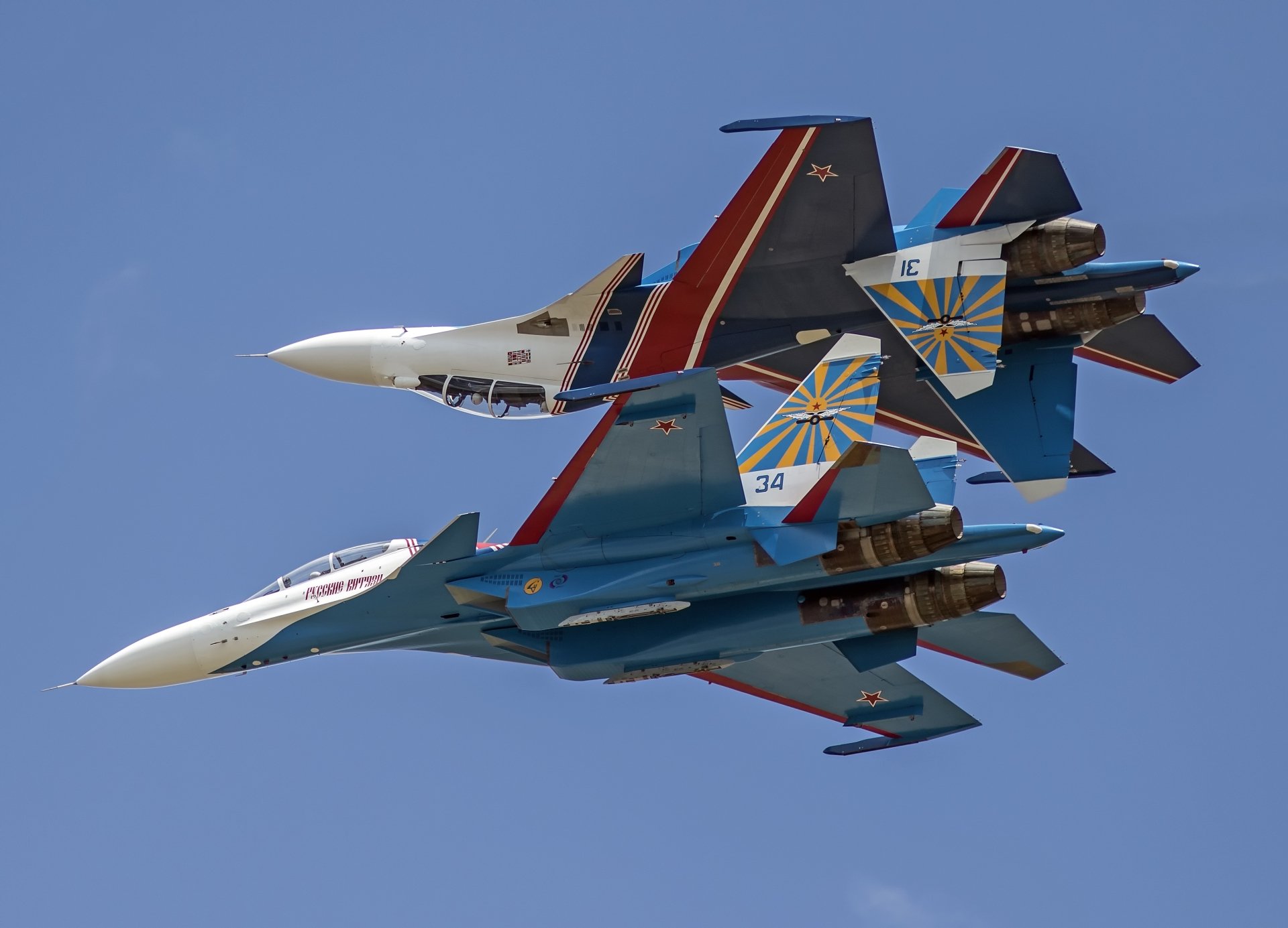Two Sukhoi Su-30 military jet fighters perform a close formation flight against a clear blue sky, captured in 4K Ultra HD quality.