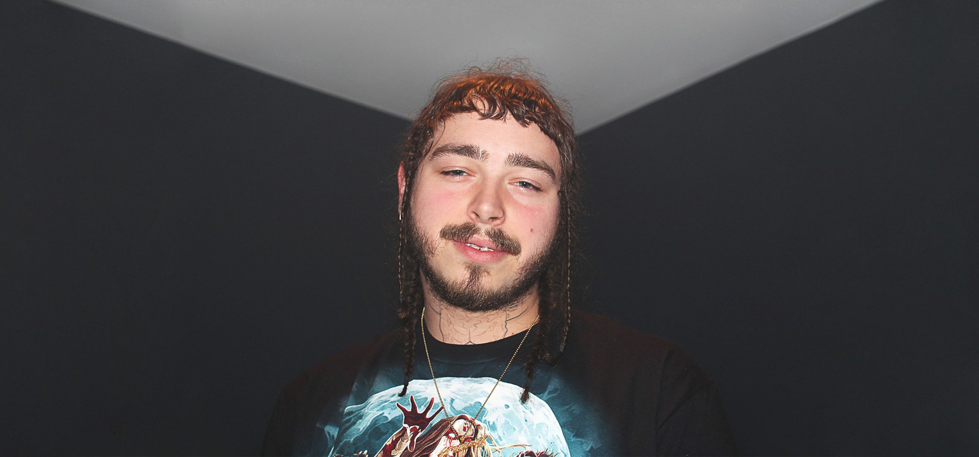 A close-up of Post Malone, featuring his signature style and braided hair, set against a dark background. This HD image serves as a striking desktop wallpaper for music fans.