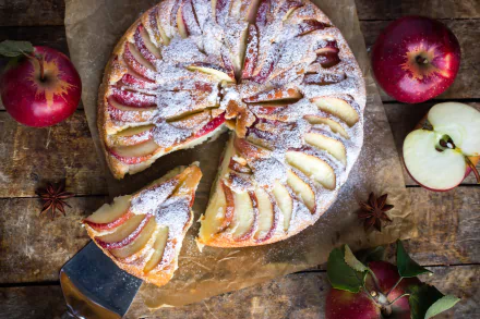 A 4K Ultra HD still life of a sliced apple pie dusted with powdered sugar, surrounded by whole and halved red apples on a rustic wooden surface.