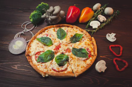 HD desktop wallpaper featuring a still life of a pizza topped with basil, surrounded by fresh mushrooms, sliced onions, bell peppers, and broccoli on a wooden surface.