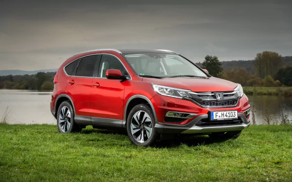 Red Honda CR-V SUV parked on grass near a lake under a cloudy sky, captured in a high-resolution 4K Ultra HD desktop wallpaper image.