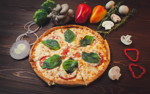 HD desktop wallpaper featuring a still life of a pizza topped with basil, surrounded by fresh mushrooms, sliced onions, bell peppers, and broccoli on a wooden surface.