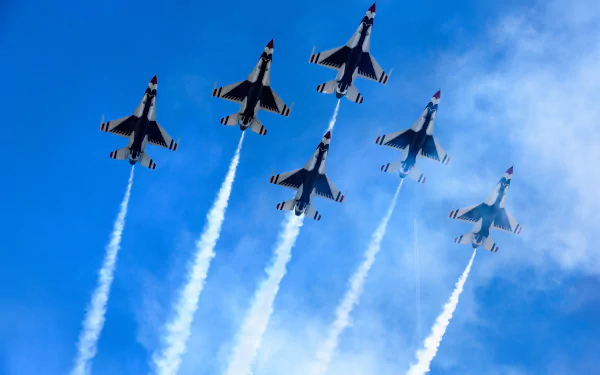 Formation of United States Air Force Thunderbirds flying General Dynamics F-16 Fighting Falcons, releasing smoke trails during an air show against a clear blue sky.