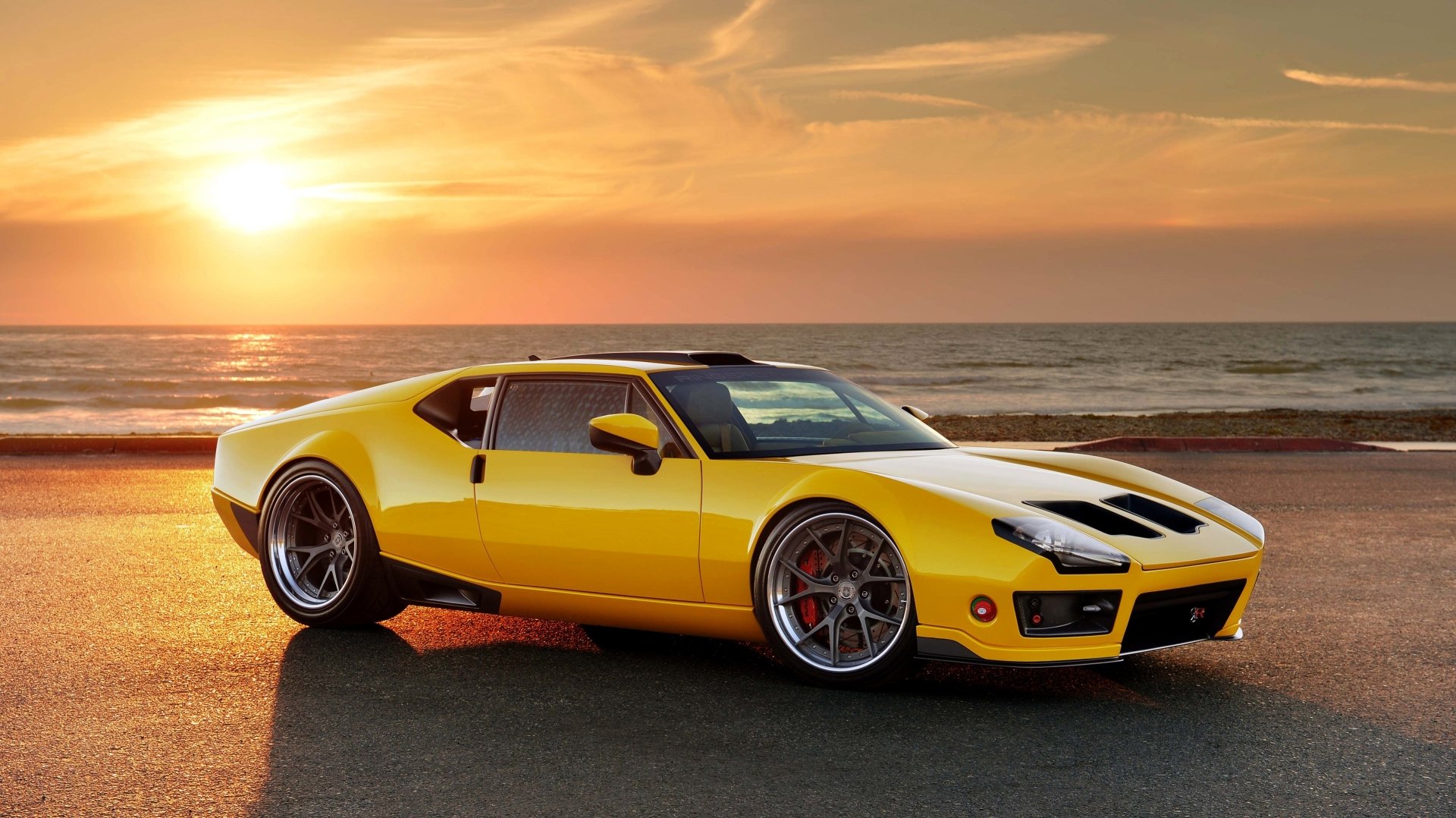A yellow De Tomaso Pantera parked by the ocean at sunset, captured in 4K Ultra HD as a PC desktop wallpaper.