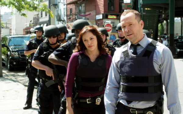 HD desktop wallpaper featuring two actors from the TV series 'Blue Bloods' walking confidently in bulletproof vests with police backup.