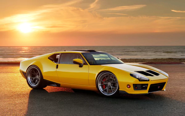A yellow De Tomaso Pantera parked by the ocean at sunset, captured in 4K Ultra HD as a PC desktop wallpaper.