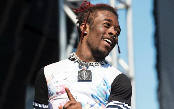 HD desktop wallpaper of a smiling person with dyed dreadlocks, performing on stage, evoking a lively musical atmosphere.