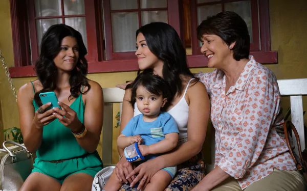 HD wallpaper from Jane the Virgin featuring three generations smiling, including a woman with a toddler on her lap.