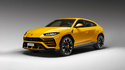 A vibrant yellow Lamborghini Urus SUV showcased in a high-definition desktop wallpaper, set against a gradient grey background.