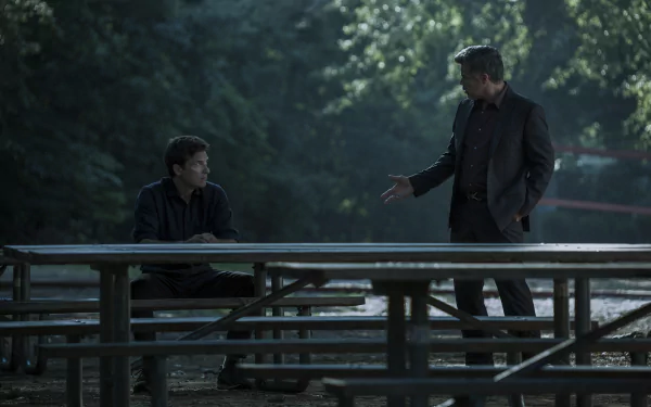 HD desktop wallpaper of a scene from Ozark showing two characters in a tense discussion at a picnic table surrounded by trees.