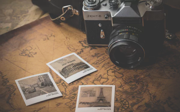 Vintage Zenit camera and old map with three retro photographs, creating a nostalgic travel-themed HD desktop wallpaper and background.