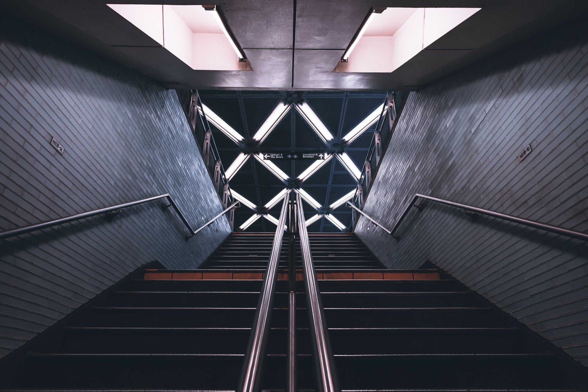 HD PC desktop wallpaper/background: subway stairs framed by stark man-made architecture, steel handrails converging toward a geometric illuminated ceiling.