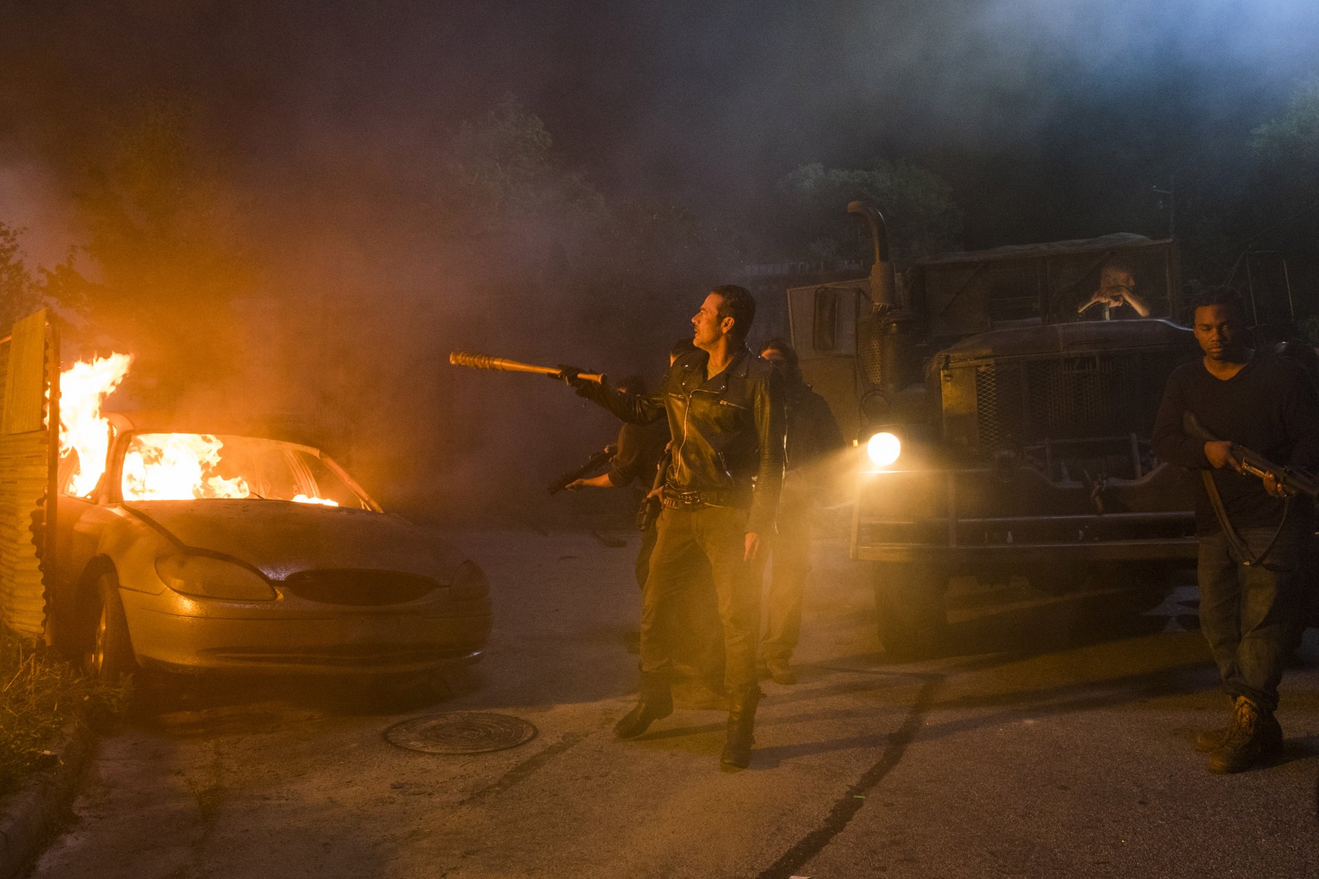 Negan (The Walking Dead) in a leather jacket wielding his barbed-wire bat amid burning car and truck at night — 4K Ultra HD PC desktop wallpaper.