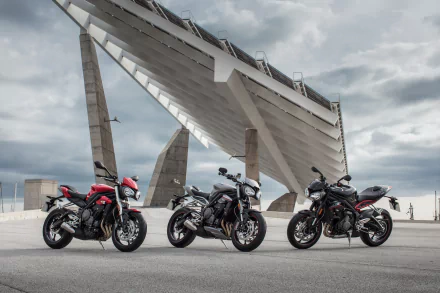 Three Triumph Street Triple motorcycles (vehicles) parked beneath an angular concrete structure, high-detail 4K Ultra HD PC desktop wallpaper background.
