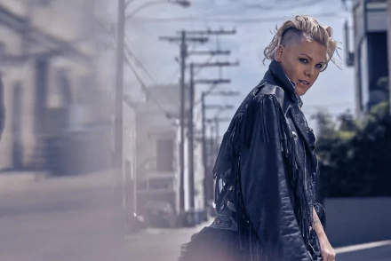 Blonde singer Pink with short hair, wearing a black leather jacket, captured in 4K Ultra HD with shallow depth of field against an urban street backdrop.