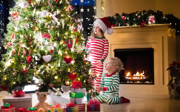 Two children in striped pajamas and Santa hats by a decorated Christmas tree and fireplace, surrounded by gifts and holiday decorations in a cozy, festive scene.