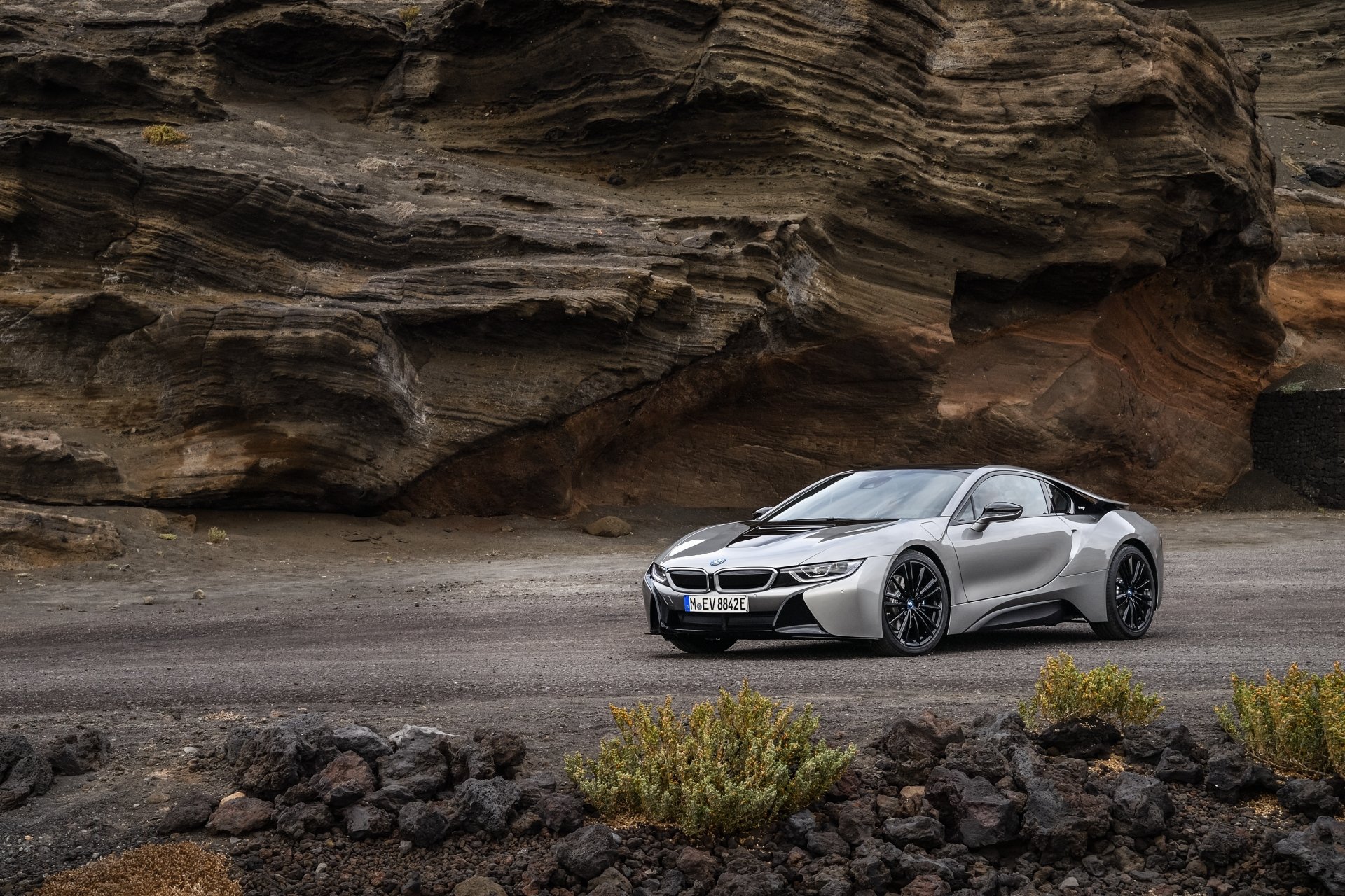Silver BMW i8 supercar parked on a rugged road with rocky cliffs in the background, captured in stunning 4K Ultra HD as a PC desktop wallpaper.