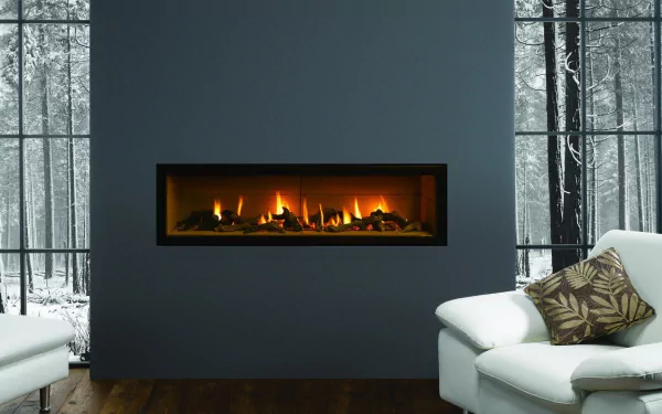 A cozy room featuring a sleek white couch and a modern fireplace, with a view of snowy trees outside, creating a warm atmosphere amidst winter's chill. Perfect HD desktop wallpaper.