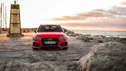 Red Audi RS4 parked on a rocky coastline at sunset, captured in 4K Ultra HD as a striking PC desktop wallpaper and background.