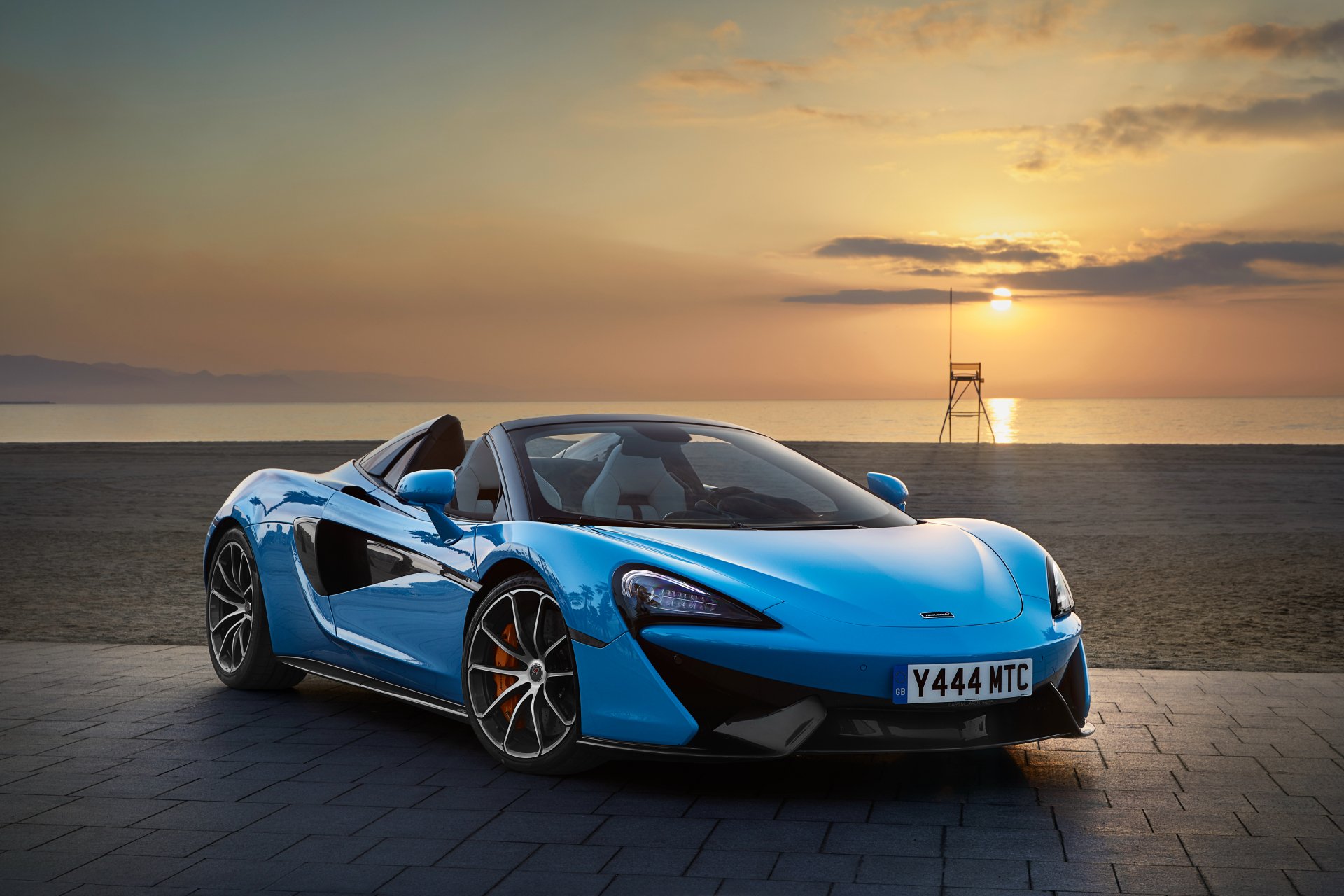 A blue McLaren 570S supercar parked on a paved surface during sunset, showcased as a 4K Ultra HD PC desktop wallpaper and background.