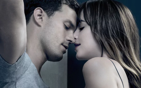 Jamie Dornan and Dakota Johnson share an intimate kiss, capturing the intense love and passion from the movie Fifty Shades of Grey in this HD desktop wallpaper.