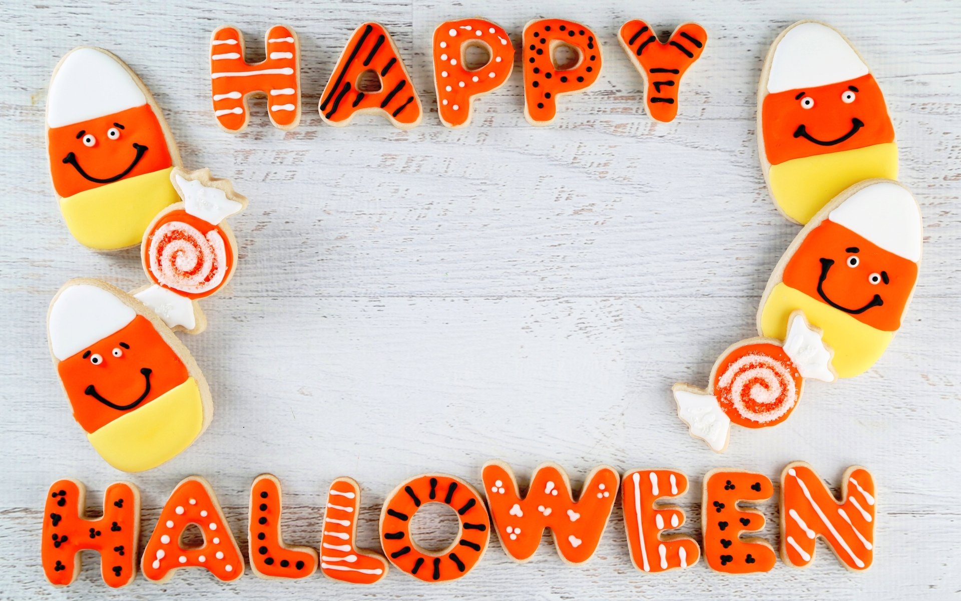 Colorful Halloween-themed cookies spelling Happy Halloween surround smiling candy corn and swirl lollipop cookies on a white wooden background in 4K Ultra HD detail.