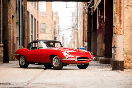 A red Jaguar E-Type car parked in an urban alley, featured as an HD PC desktop wallpaper and background.