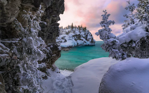 Snow-covered mountain landscape in Ontario, Canada, overlooking the turquoise waters of Lake Huron during winter, captured in a high-definition desktop wallpaper.