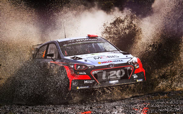HD desktop wallpaper featuring a rally car speeding through mud, showcasing intense rallying action and dynamic sports energy.