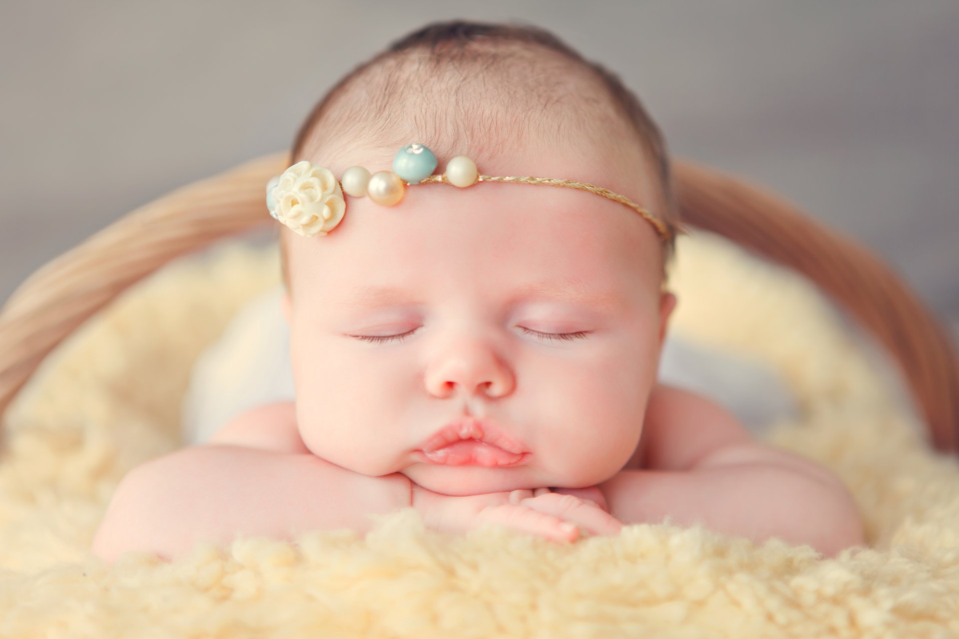 Close-up of a sleeping baby wearing a delicate headband, captured in a soft, warm setting. This 4K Ultra HD image highlights adorable, peaceful innocence.