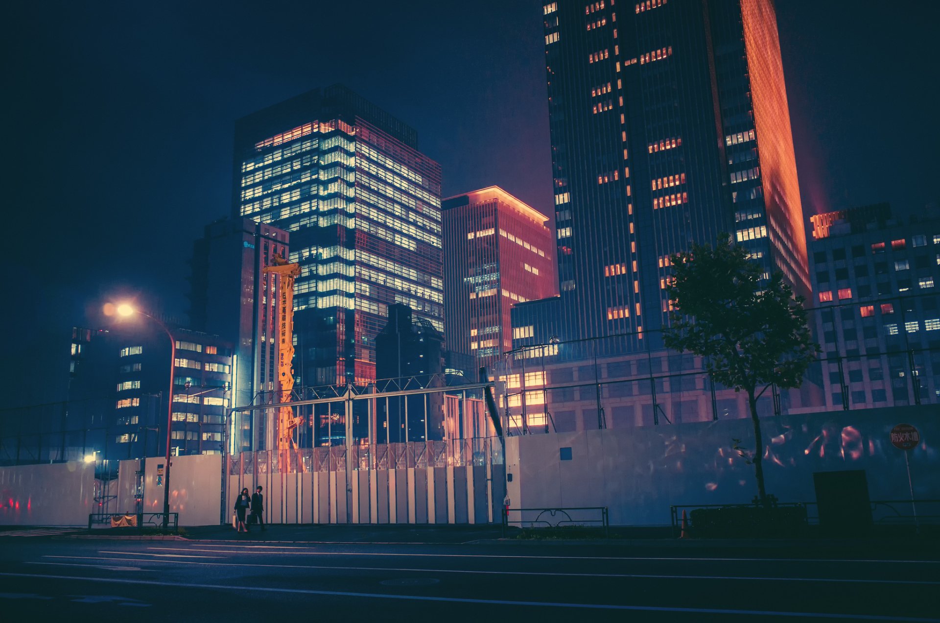 HD PC desktop wallpaper of a neon-lit Japanese cityscape at night, showcasing tall man-made skyscrapers glowing against the dark sky.