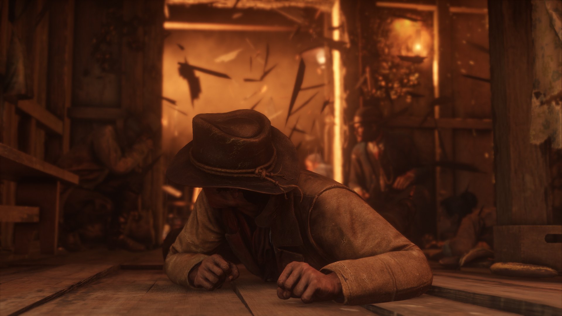 HD PC desktop wallpaper from the video game Red Dead Redemption 2, showing a cowboy in a dimly lit wooden cabin.