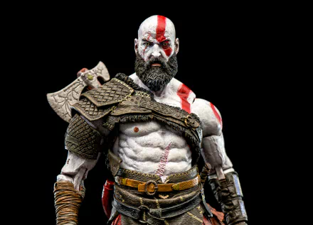 HD desktop wallpaper featuring a detailed figurine of Kratos from the video game God of War (2018), showcasing his muscular build, armor, and red war paint.