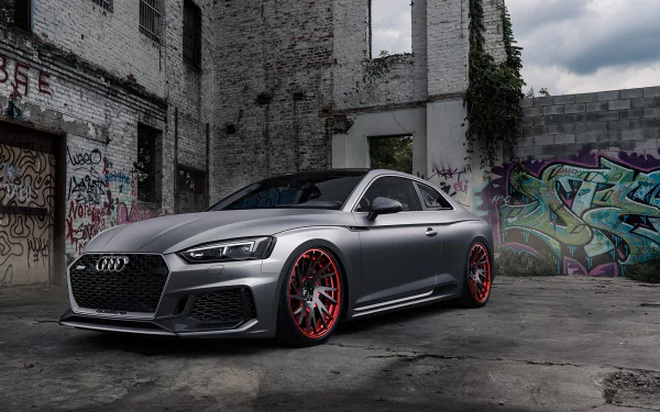 HD PC desktop wallpaper featuring a sleek silver Audi RS5 parked in an urban setting with graffiti-covered walls and a moody sky.
