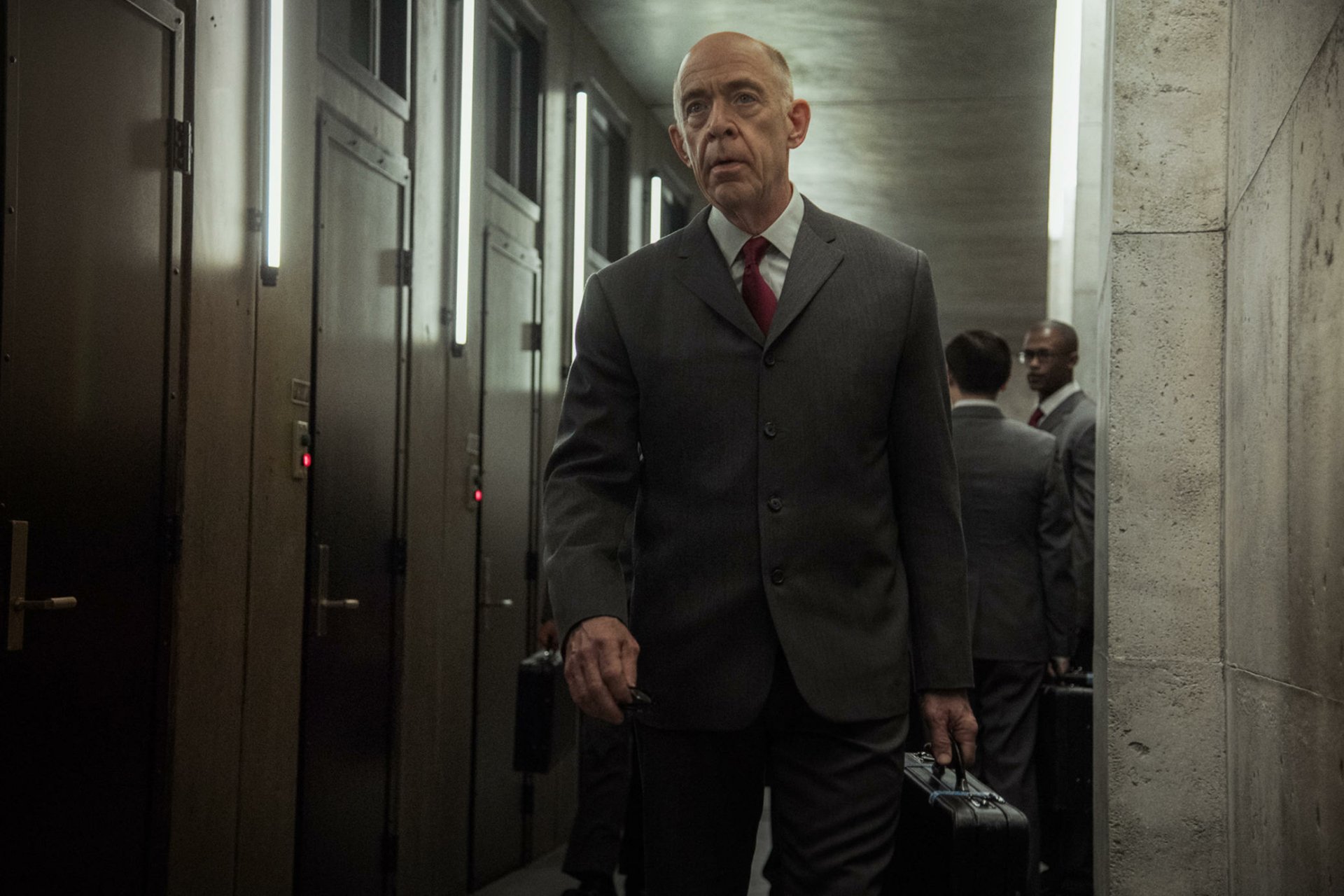 HD wallpaper featuring a man in a suit walking in a dimly lit corridor, a scene from the series Counterpart.