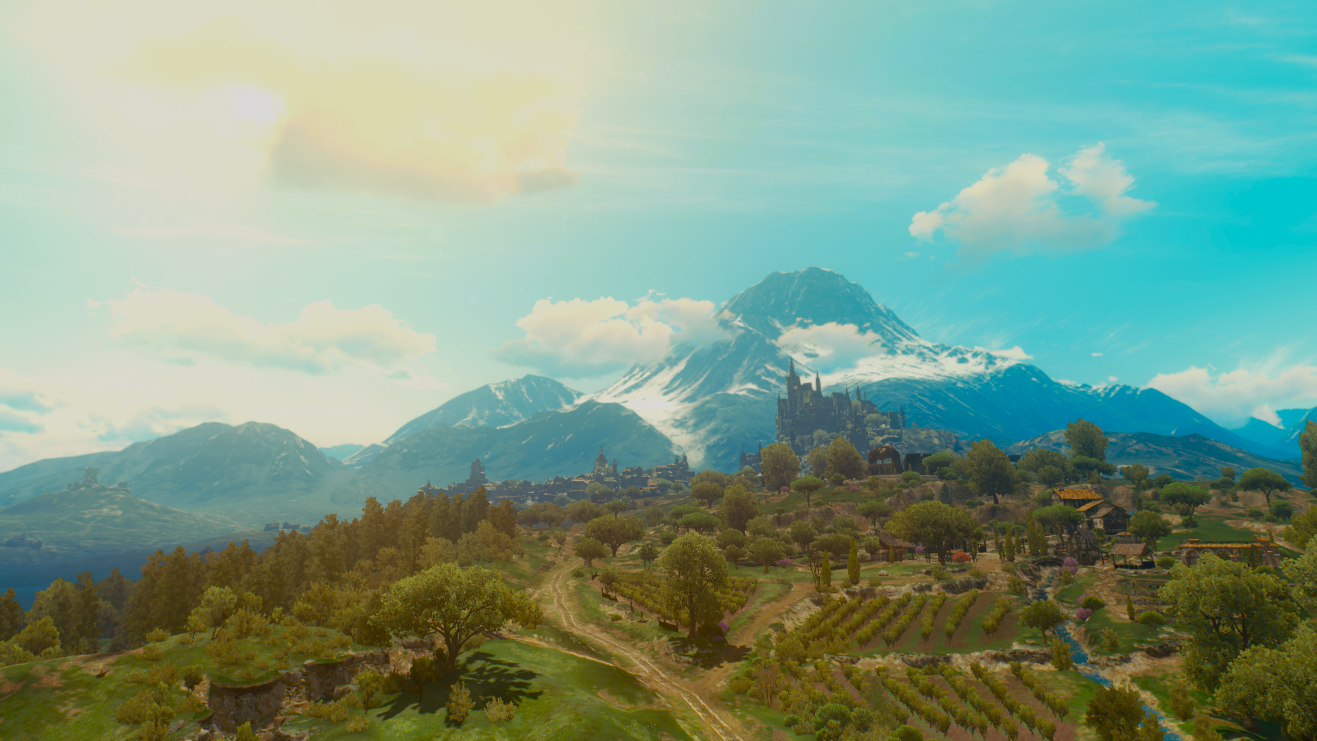HD PC desktop wallpaper featuring a scenic landscape from the video game The Witcher 3: Wild Hunt with mountains, forests, and a bright sky.