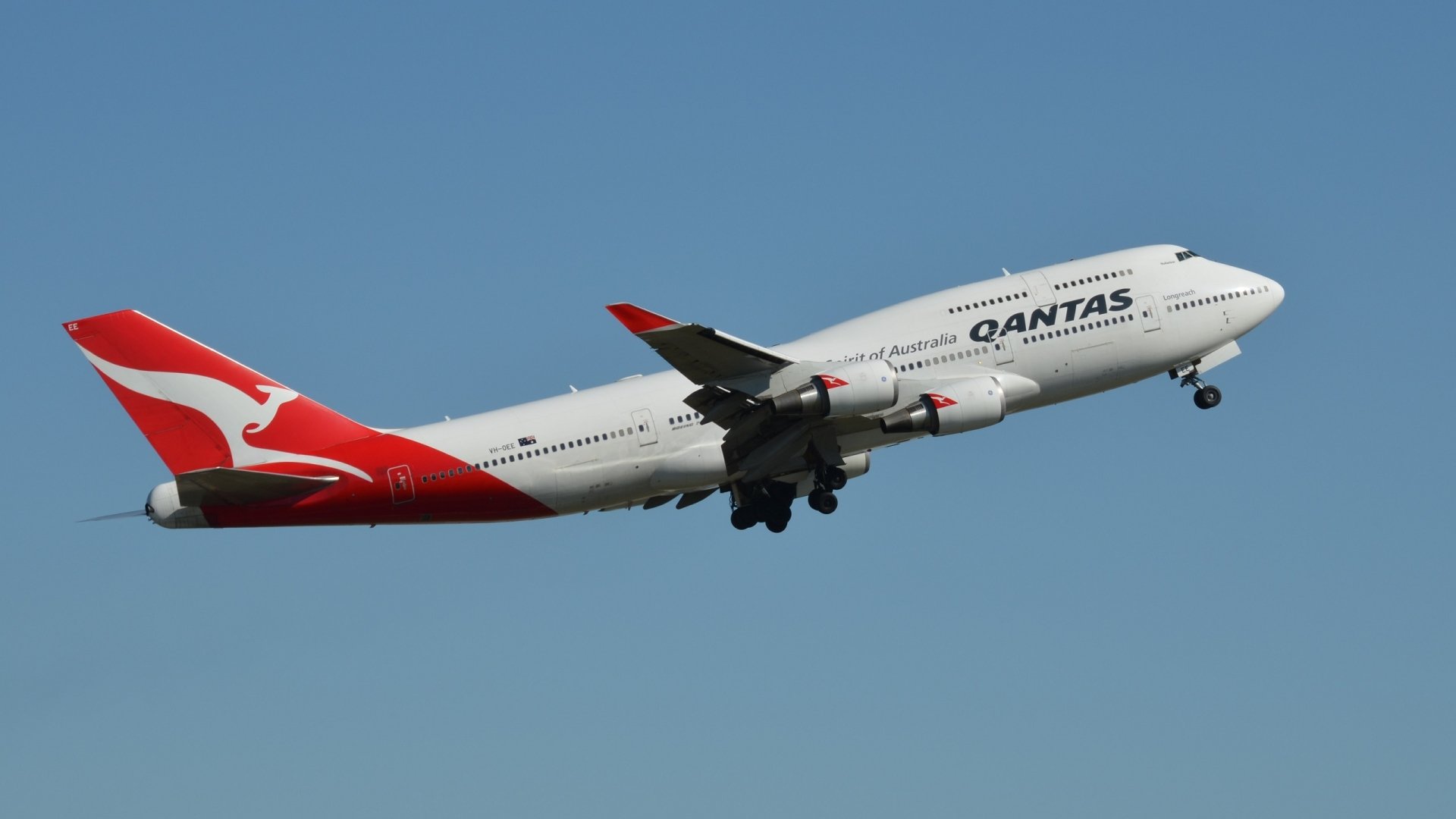A Qantas Boeing 747 passenger plane ascending against a clear blue sky, captured in high definition as a desktop wallpaper background.