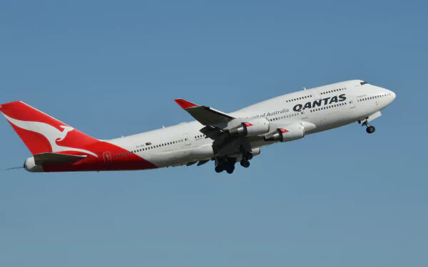 A Qantas Boeing 747 passenger plane ascending against a clear blue sky, captured in high definition as a desktop wallpaper background.